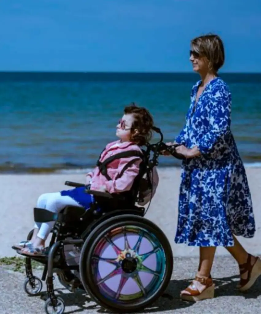 Une femme qui se balade au bord de la mer avec sa fille polyhandicapée.